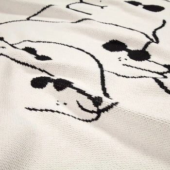 The Slowdown Studio Dawgs Mini Blanket features a playful white textured fabric with abstract dog faces in sunglasses, crafted from recycled cotton—perfect for adding style and fun to any space.