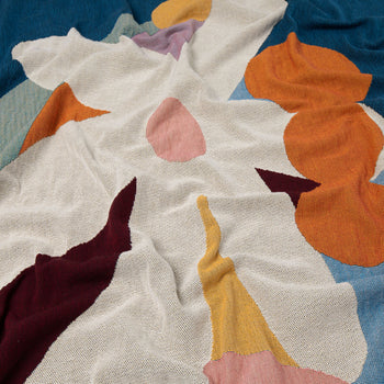 The Slowdown Studio Delaney Throw by Slowdown Studio features abstract, colorful shapes in orange, blue, yellow, maroon, pink, and white atop a soft eco-friendly fabric with an irregular overlapping pattern and gentle folds.