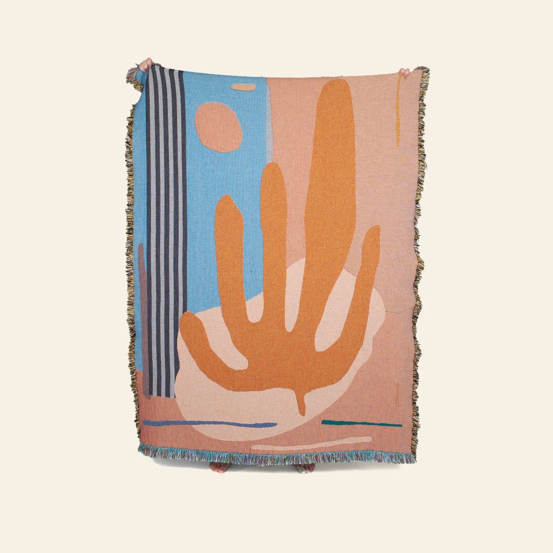The Slowdown Studio Hazlewood Throw by Slowdown Studio is a woven blanket featuring bold organic shapes, vertical stripes, and fringed edges in orange, blue, beige, and pink tones against a plain light background.