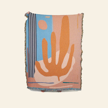 The Slowdown Studio Hazlewood Throw by Slowdown Studio is a woven blanket featuring bold organic shapes, vertical stripes, and fringed edges in orange, blue, beige, and pink tones against a plain light background.