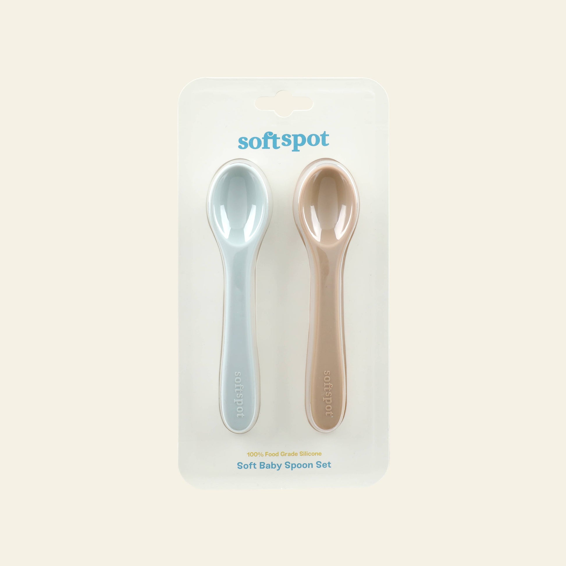 Soft Spot Soft Baby Spoons, Set of 2, are gently displayed side by side in clear packaging. Perfect as babys first spoons, these silicone utensils from Soft Spot soothe teething gums and make feeding easy against a light cream background.