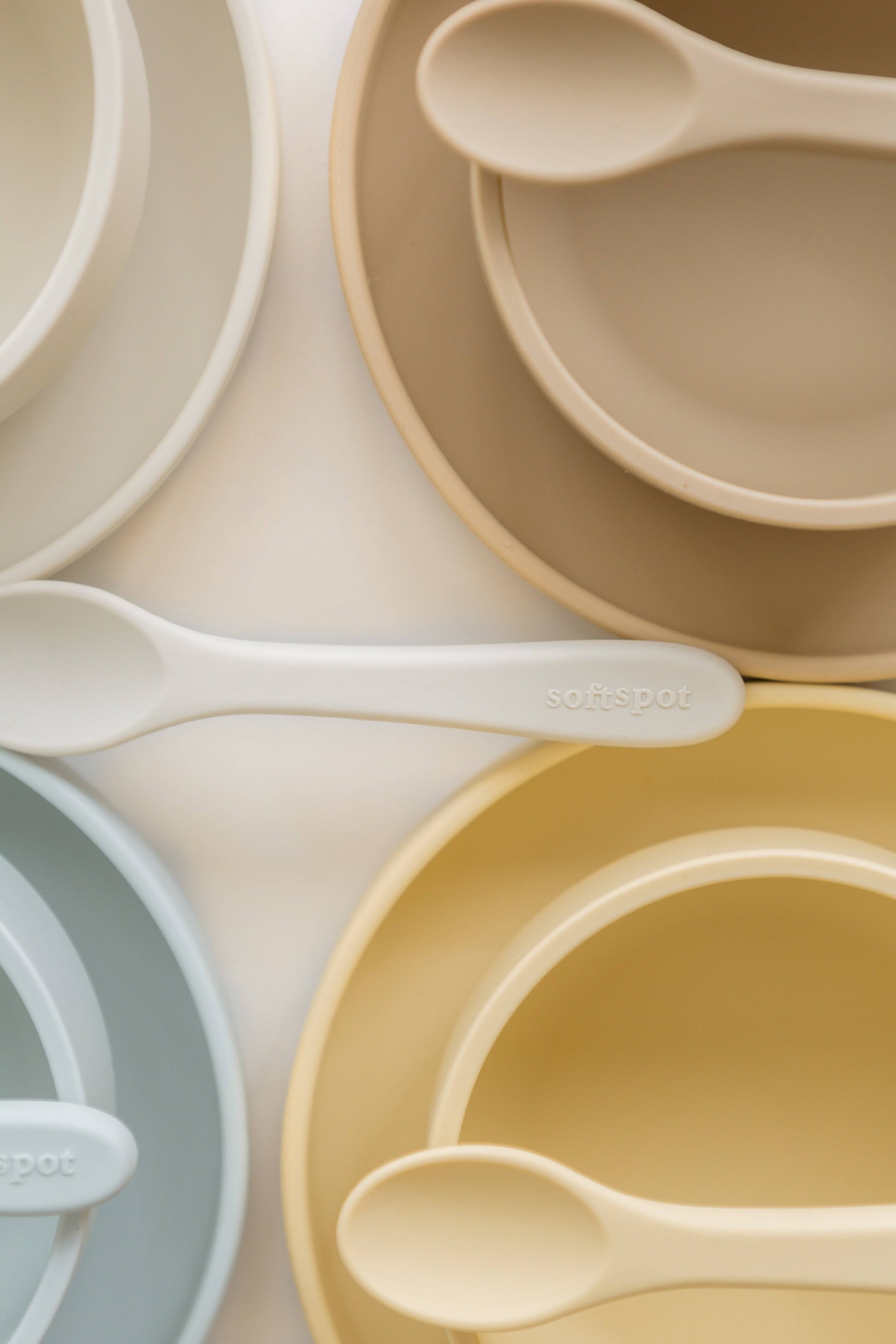 A set of Soft Spot Soft Baby Spoons, Set of 2 by Soft Spot, in gentle neutral colors, is shown arranged on a light surface; each spoon is ideal for babys first bites and gentle on teething gums.