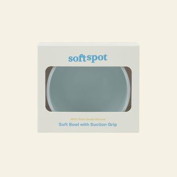 Soft Spot Soft Suction Bowl in light blue comes in white packaging with a clear window. Soft Spot, Soft Suction Bowl, and 100% Food Grade Silicone are printed on the front.