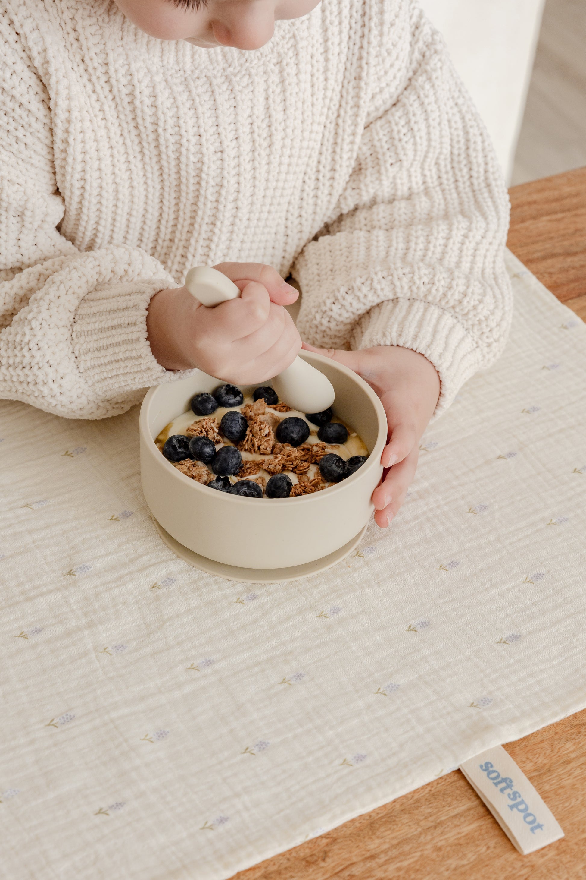 Three Soft Spot Soft Tea Towels (Set of 3) from Soft Spot in pastel cream, lavender, and blue hang above a beige countertop. Below them, a white bowl with two green pears sits next to a white tiled wall.