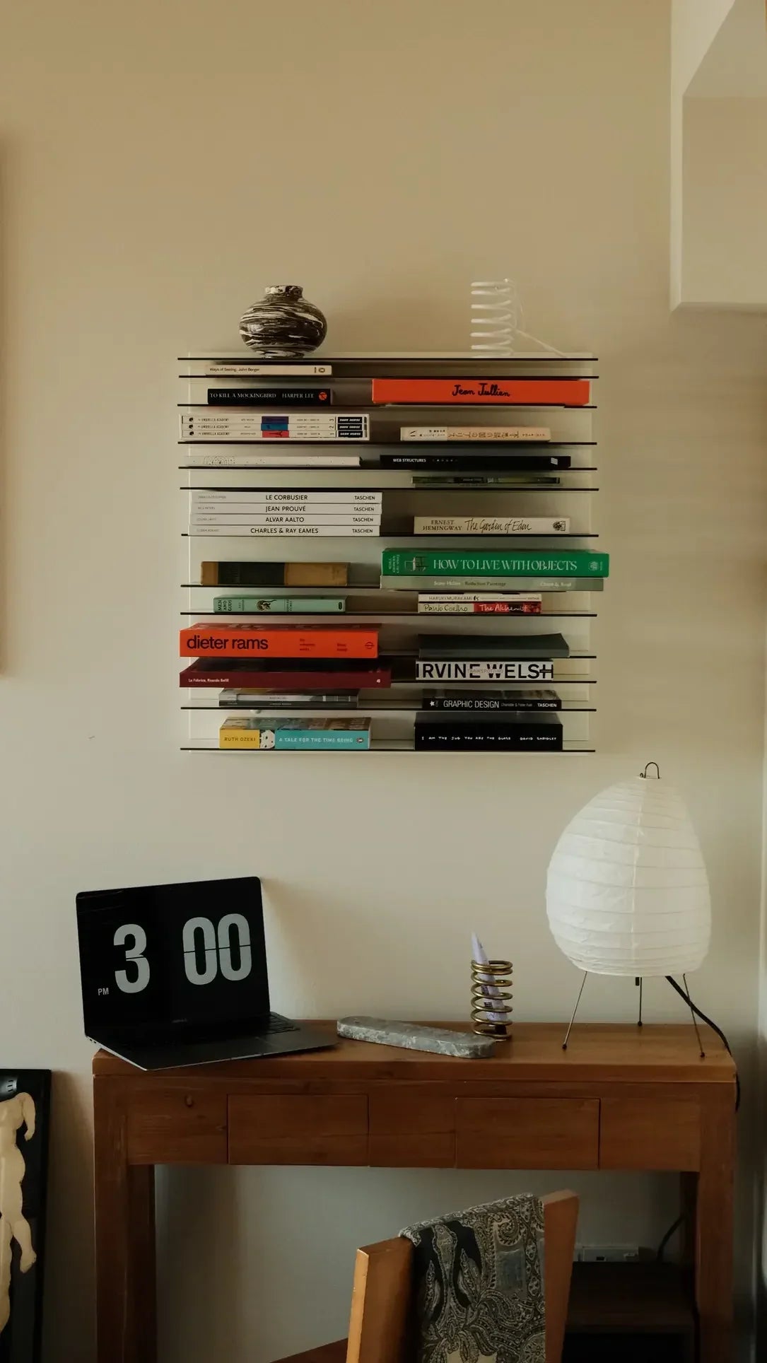 The Spectrum Paperback Wallsystem 60x60 by Spectrum features a minimalist rectangular vent cover with horizontal slats and two screw holes, designed to complement any modern wall system. Photographed against an off-white background.