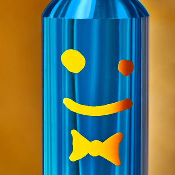 Staff The Plunger by Staff is a shiny blue metallic bathroom essential featuring a yellow smiley face and bow tie design, set against a golden yellow background.