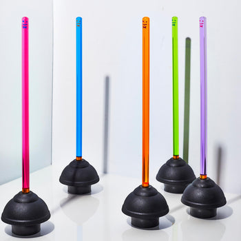 Five Staff The Plunger by Staff—black rubber plungers with neon vertical rods in pink, blue, orange, green, and purple—stand upright on a white reflective surface against a plain white background.