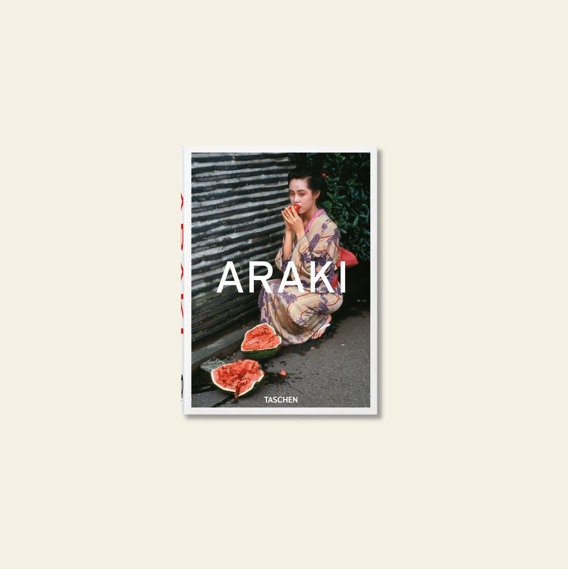 A woman in a patterned kimono sits on the ground eating watermelon on the TASCHEN Araki book cover, highlighting iconic Japanese photography.