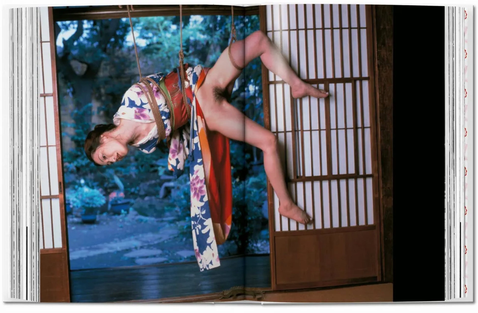 A person in a floral kimono, suspended by ropes with eyes closed, channels TASCHEN Araki's photography, set before shoji screens framing a lush garden—an evocative scene inspired by the iconic TASCHEN brand.