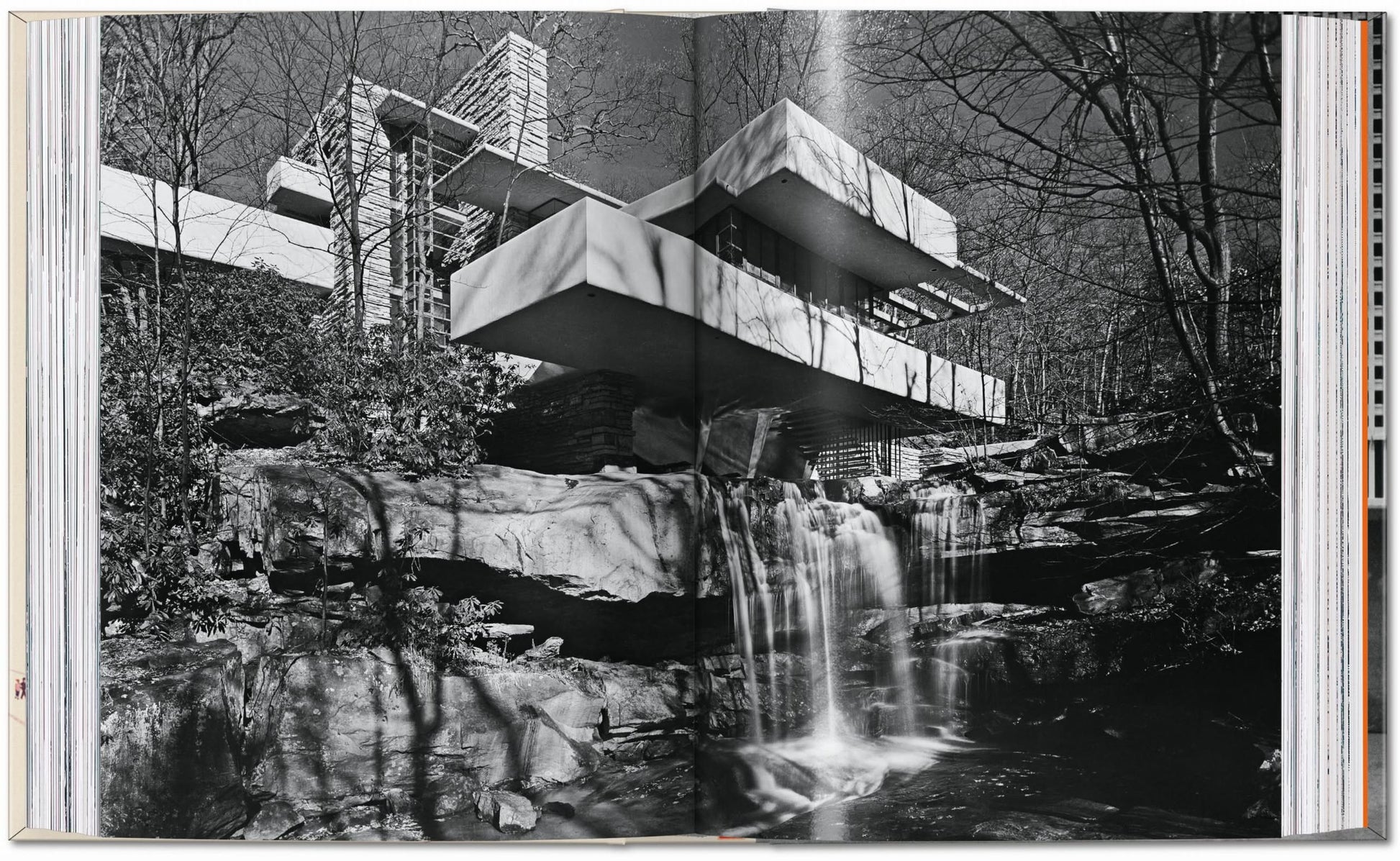Open book displays a black-and-white photo of Frank Lloyd Wright’s iconic house above a waterfall, surrounded by trees—an architectural masterpiece highlighted in the TASCHEN Frank Lloyd Wright edition by TASCHEN.