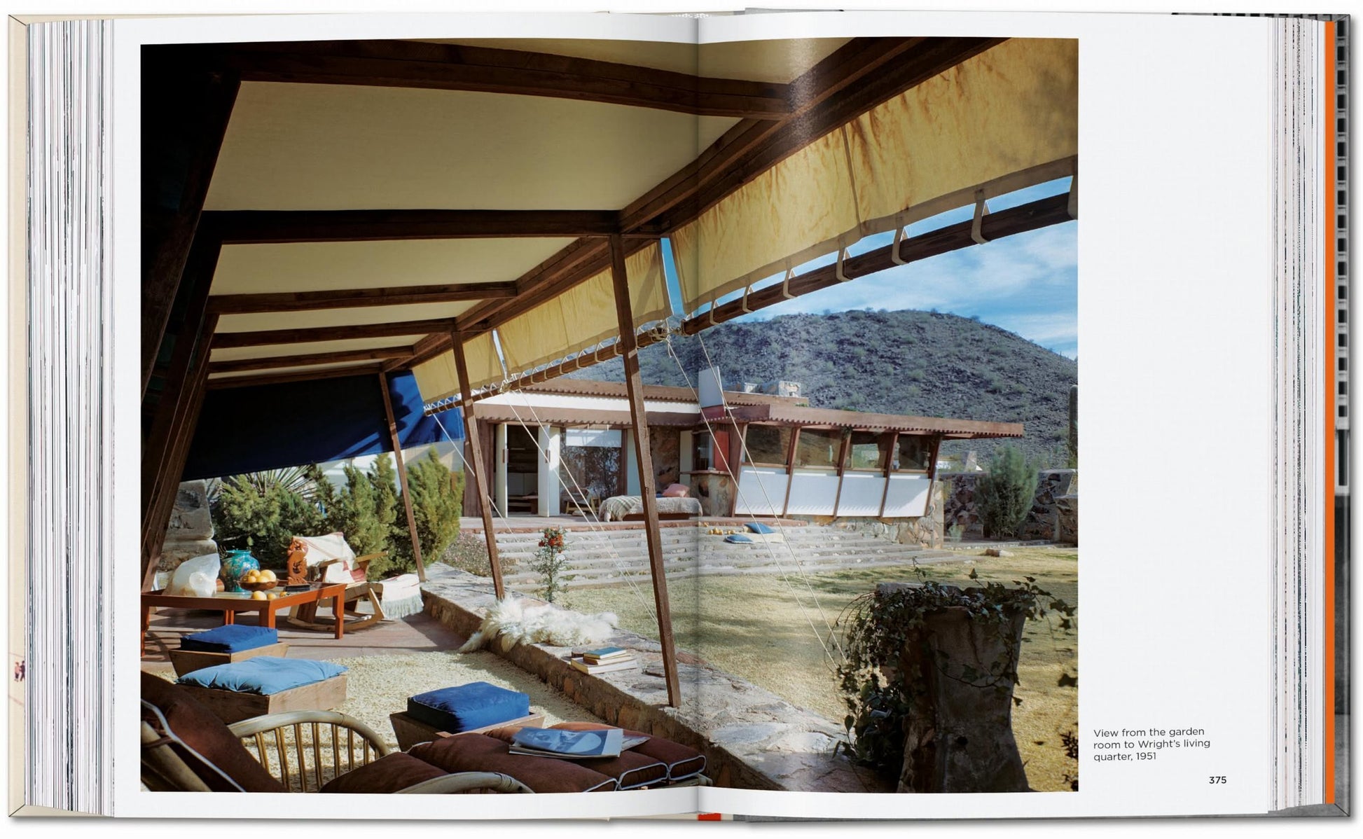 A photo inspired by Frank Lloyd Wright’s architecture—modern house with large windows and canvas awnings, patio seating, desert garden, and mountains—featuring the TASCHEN Frank Lloyd Wright book by TASCHEN.