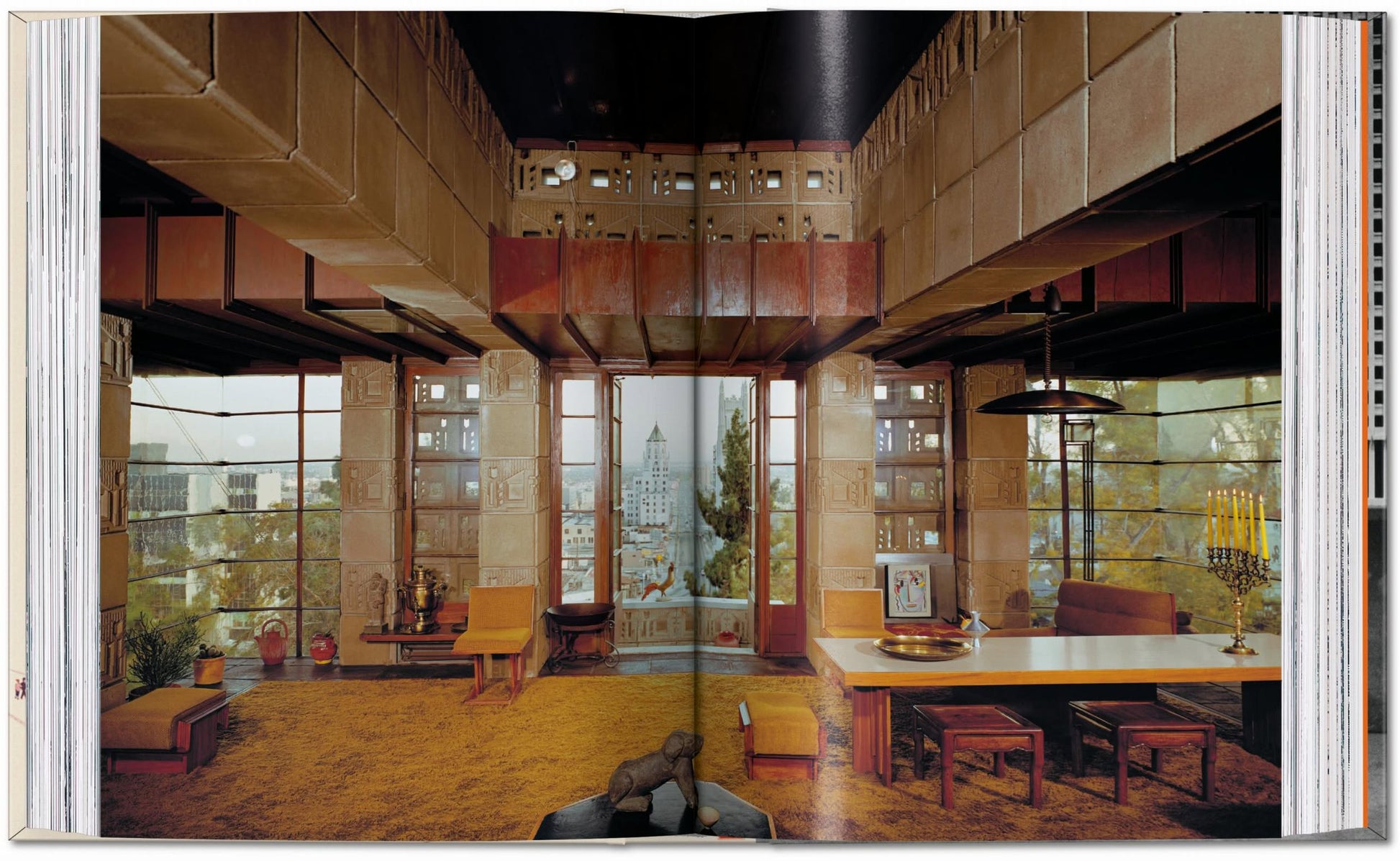 A spacious, elegant room with Frank Lloyd Wright-inspired geometric walls, city views, and modern décor—featured in a photo from the TASCHEN Frank Lloyd Wright book by TASCHEN.