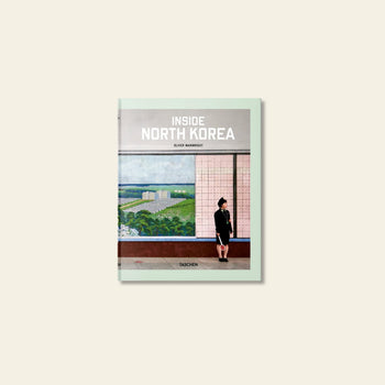 The TASCHEN Inside North Korea book cover by TASCHEN shows a person indoors in front of a mural with green fields and buildings, evoking architectural exploration. The product name is displayed at the top.