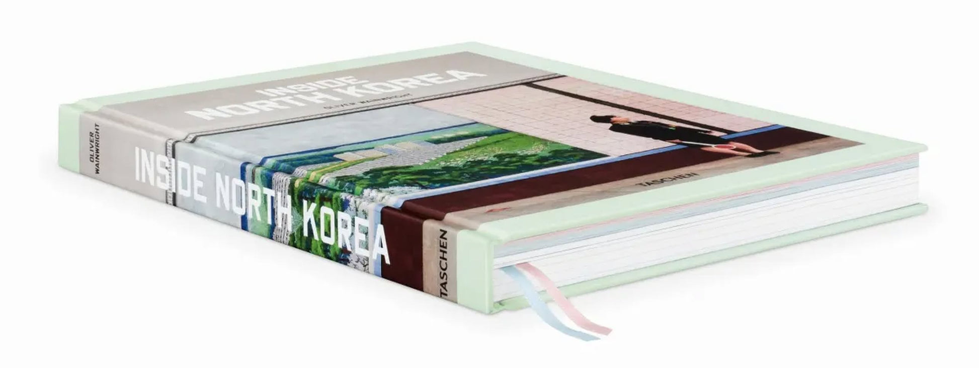 The TASCHEN Inside North Korea hardcover book by TASCHEN lies closed, its cover featuring a striking photo of North Korean architecture and several pastel-colored ribbon bookmarks visible.
