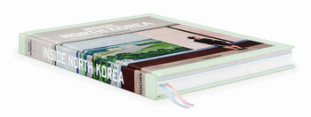 The TASCHEN Inside North Korea hardcover book by TASCHEN lies closed, its cover featuring a striking photo of North Korean architecture and several pastel-colored ribbon bookmarks visible.