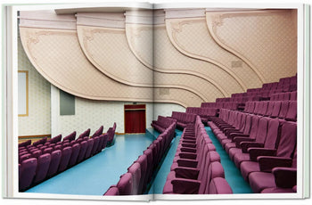 An open book, TASCHEN Inside North Korea by TASCHEN, features a photo of an empty auditorium with purple seats, blue flooring, and ornate wall panels—capturing modern design in North Korea.