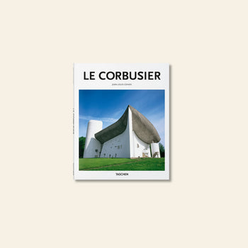Book cover of TASCHEN Le Corbusier features a striking photograph of the sculptural Notre-Dame du Haut chapel with its curved concrete roof against a blue sky, highlighting an iconic moment in modern architecture. Brand: TASCHEN.