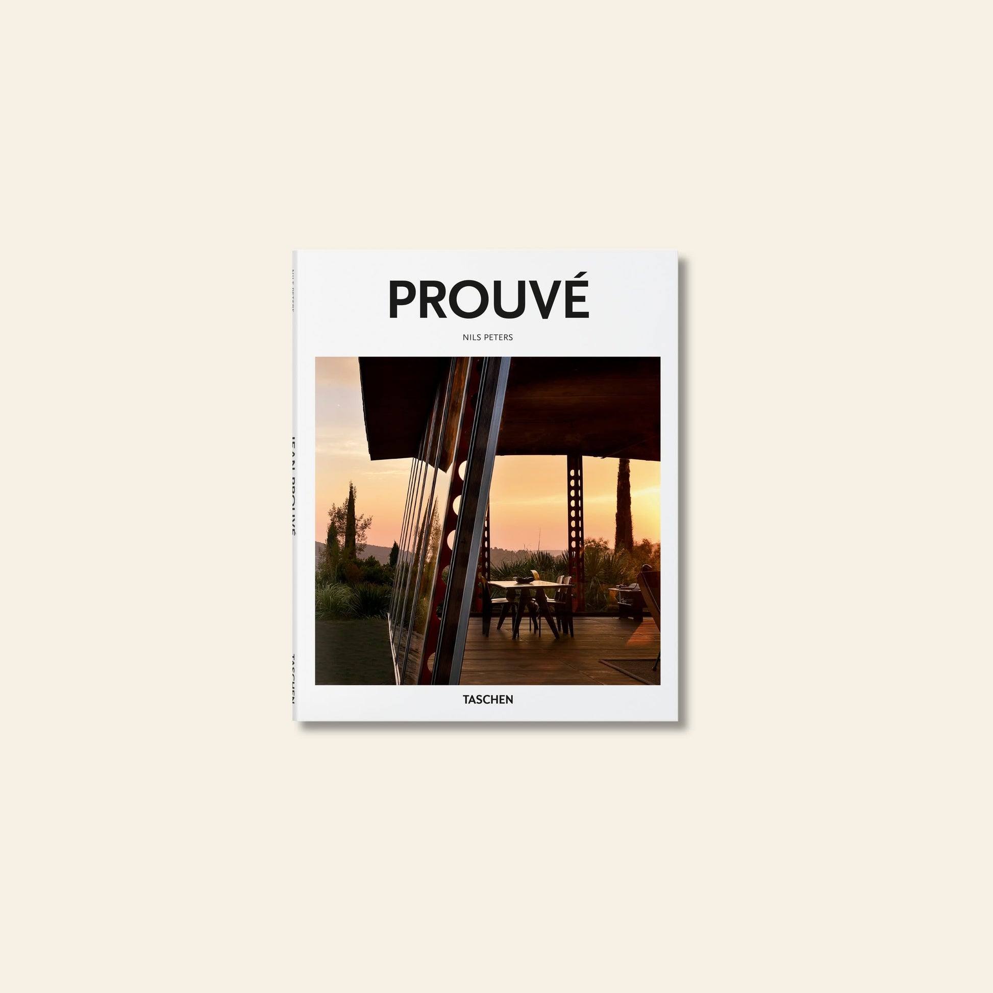 The cover of TASCHEN Prouvé by Nils Peters, published by TASCHEN, features a modern glass building at sunset amid trees, reflecting Jean Prouvé’s innovative approach to midcentury materials and design.