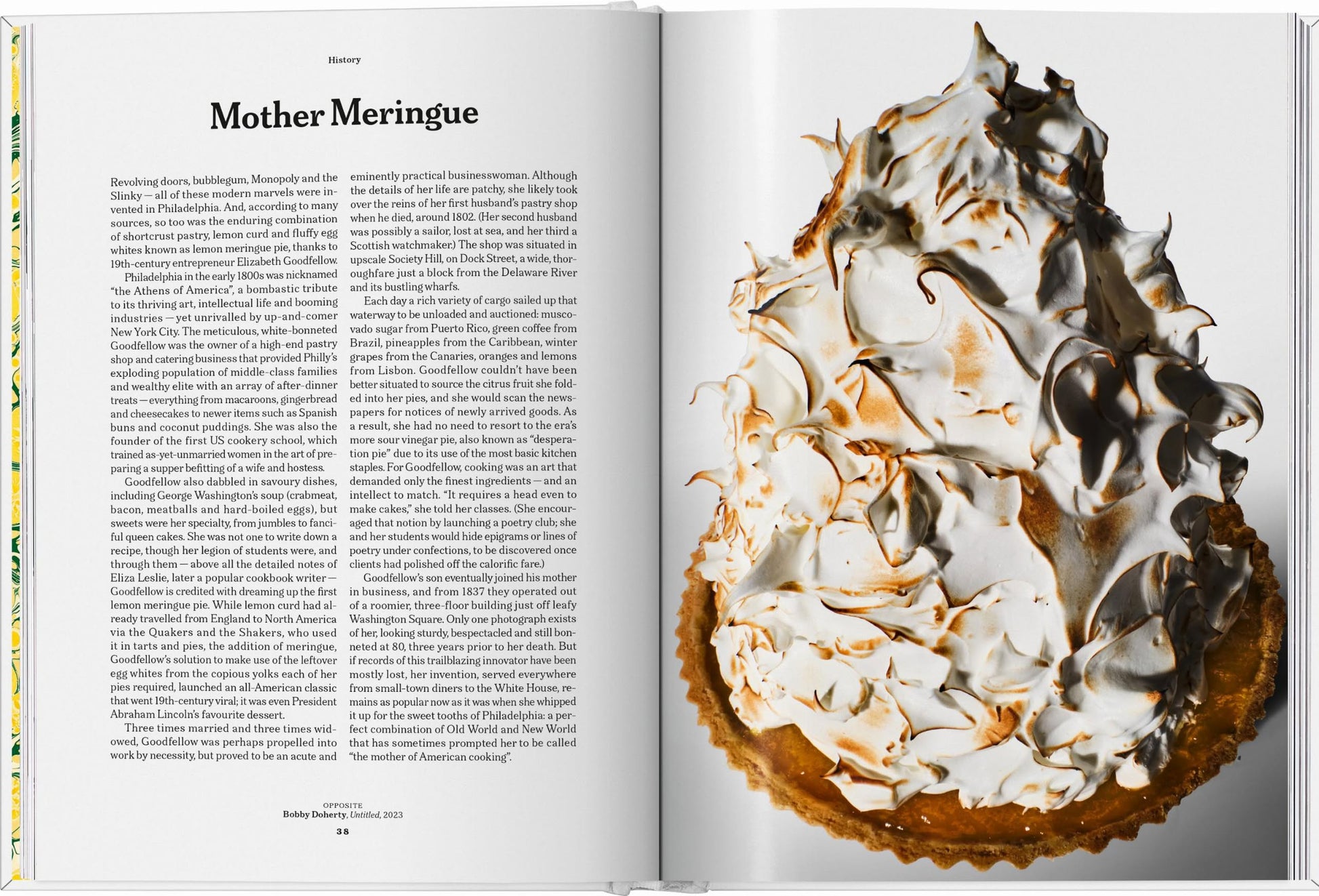 An open TASCHEN The Gourmands Lemon: A Collection of Stories and Recipes book features the article “Mother Meringue” on the left page and a golden-brown lemon meringue pie on the right, shown against a white background.