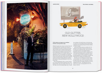 An open TASCHEN The New York Times Explorer: 100 Dream Trips Around the World book reveals a man in a suit outside a restaurant at night, while the right page shows a woman in a yellow convertible, capturing iconic dream destinations.