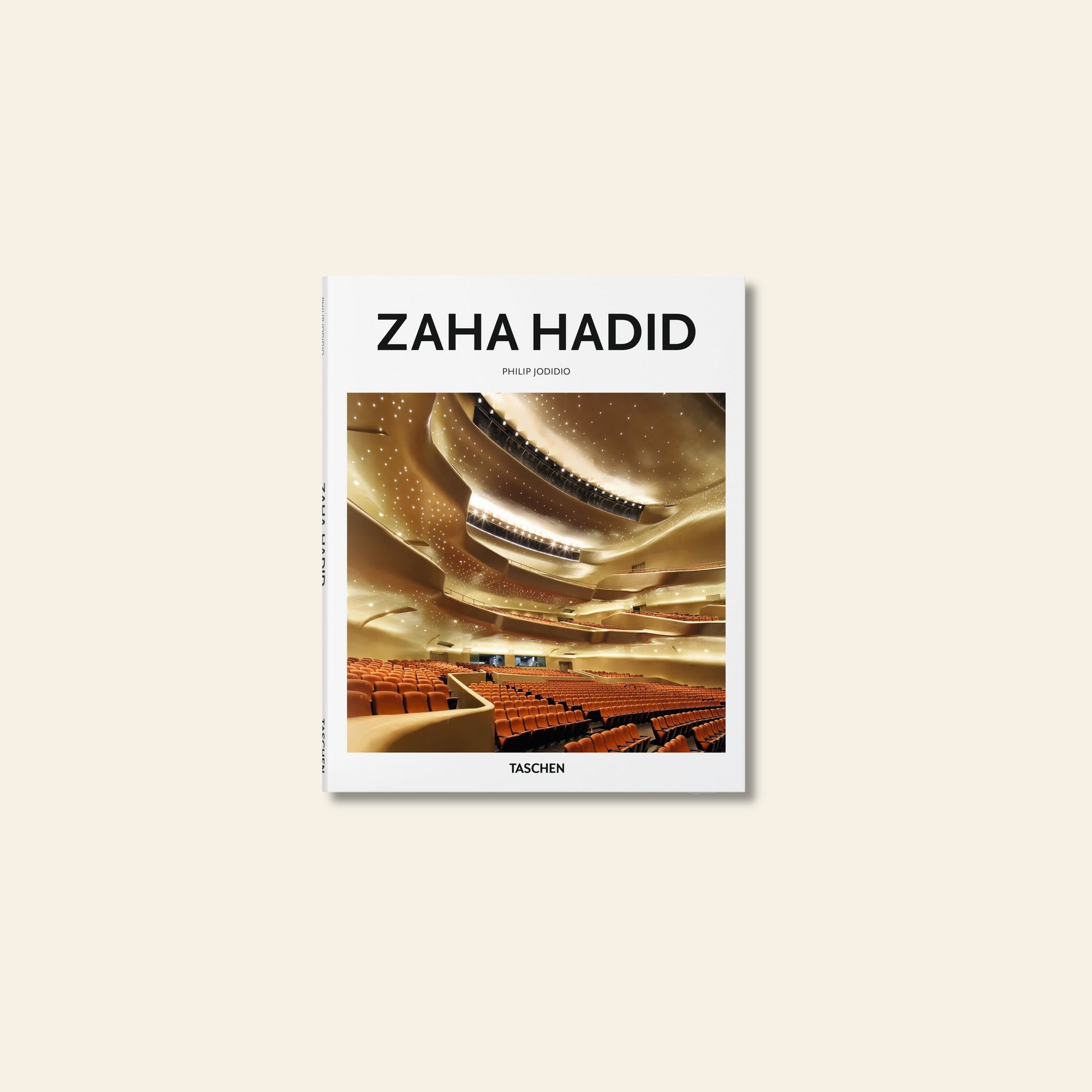 The image features the TASCHEN Zaha Hadid book by TASCHEN, with a modern curved-ceiling auditorium on the cover, celebrating the iconic work of the renowned architect.