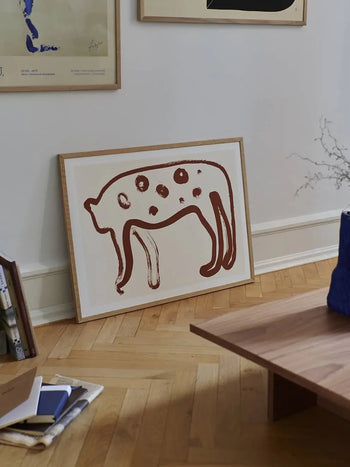 A framed Jaguar 01 abstract art print by Anastasia Krasilnikova from The Poster Club (50x70 cm) leans against a white wall in a modern room with wooden flooring and minimal decor.