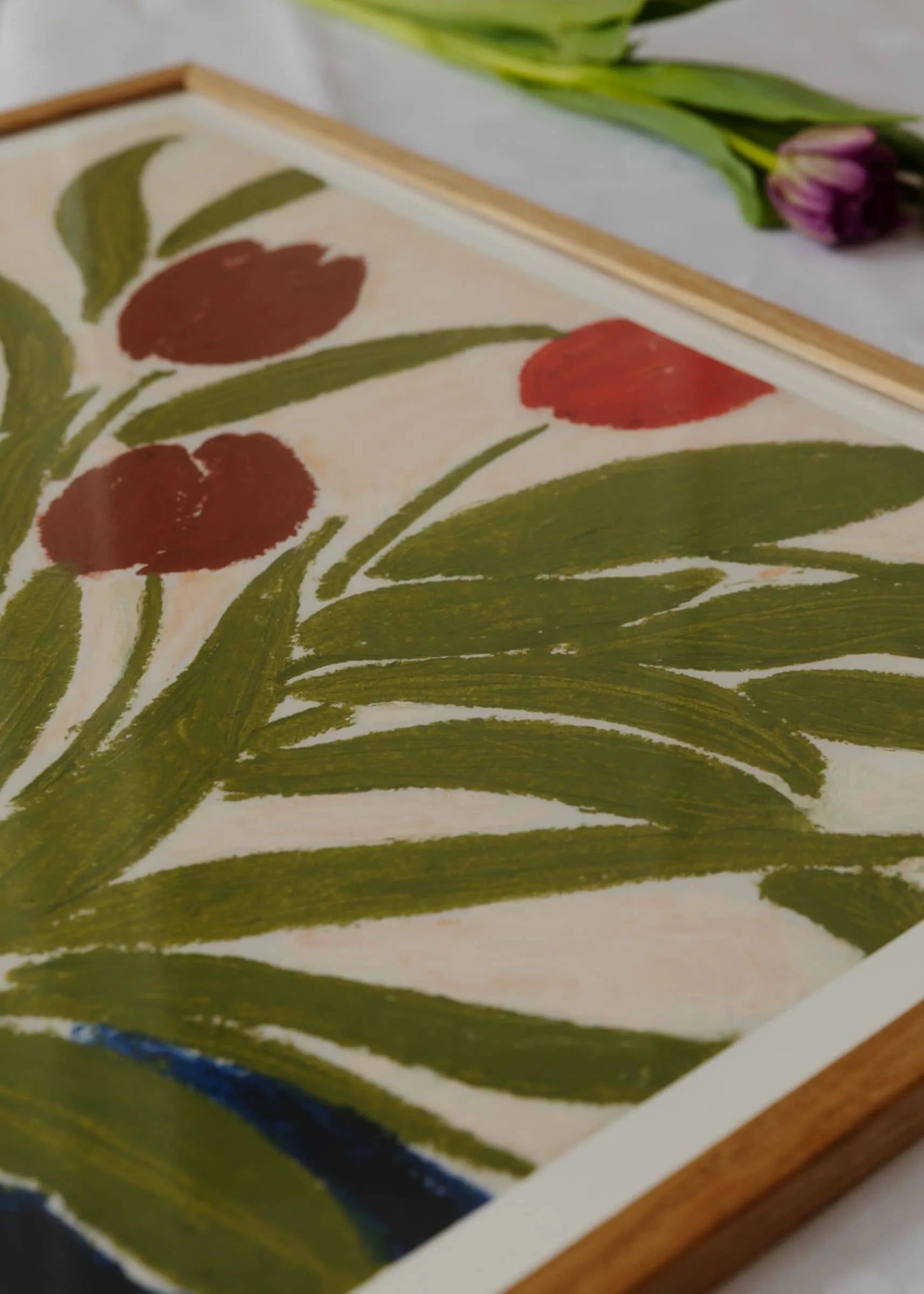 A close-up of Tulips in a Blue Vase by Anine Cecilie Iversen, showing green leaves and red-brown flowers in an abstract style. Available as a 30x40 cm fine art giclée print from The Poster Club.