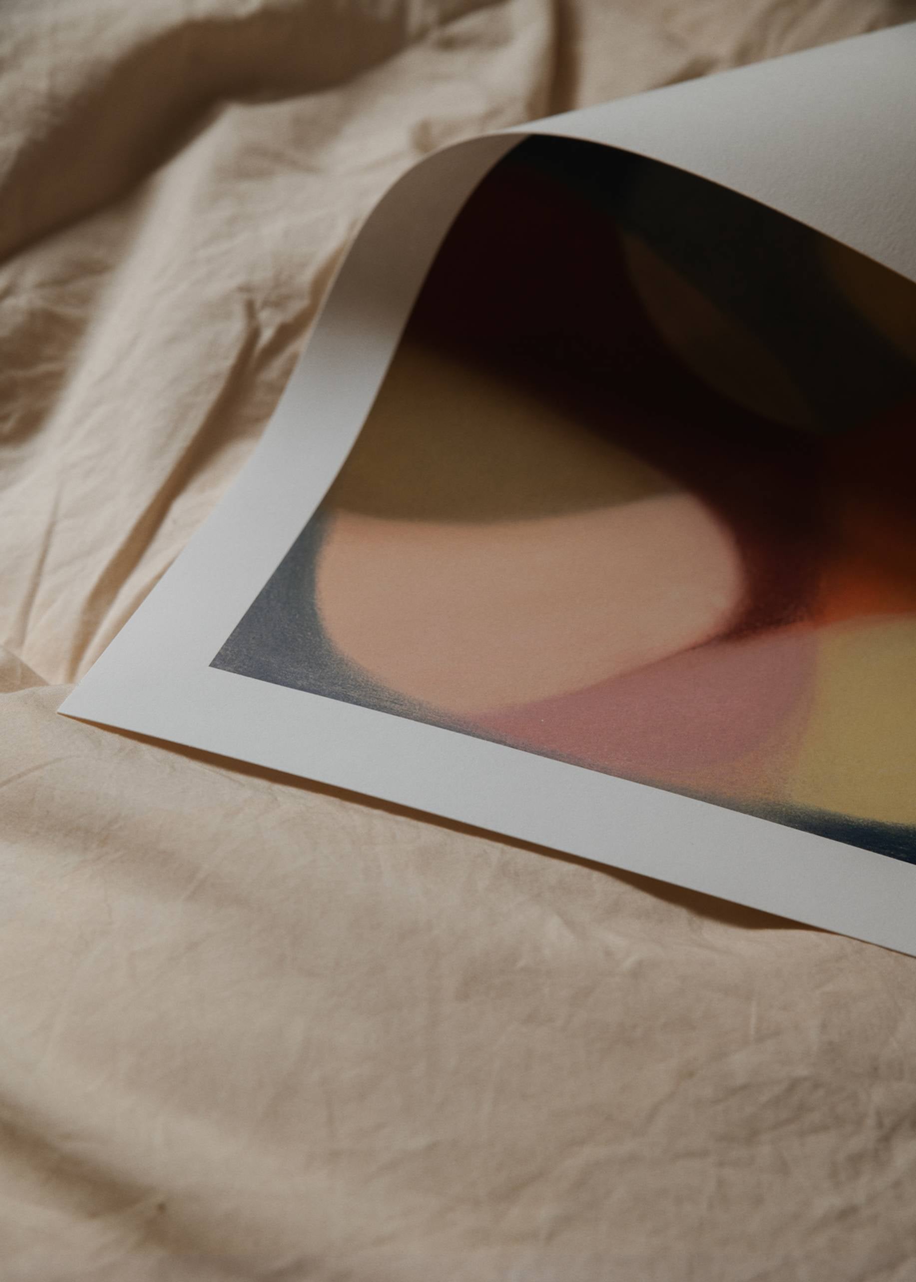 A close-up of The Poster Club Berit Mogensen Lopez - Increase (50x70) art print, featuring soft, blurred shapes in warm hues on a crumpled beige fabric, available from The Poster Club.