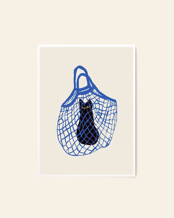 The Poster Club Chloe Purpero Johnson - The Cat’s In The Bag (50x70) features a black cat sitting in a blue mesh bag with wide eyes, set against a beige background, in this fine art print by The Poster Club.