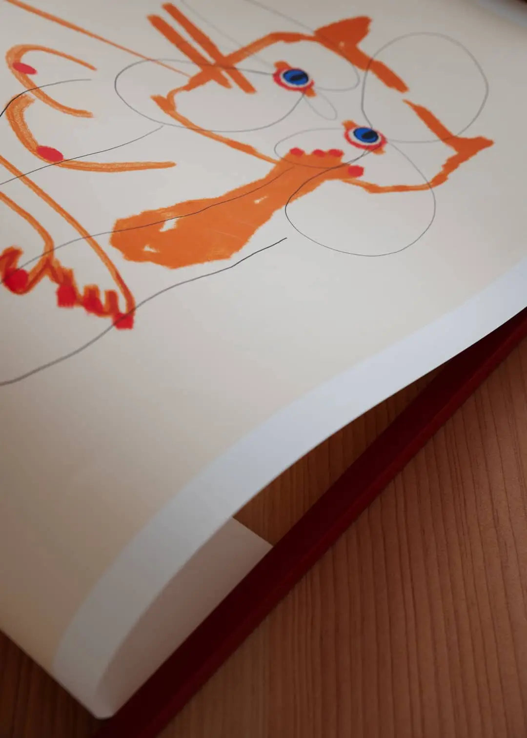 A Poster Club print, Das Rotes Rabbit - Afternoon Communiqué (50x70), is displayed on a wooden surface, its vivid abstract design and curved page edge evoking fine art prints by The Poster Club.