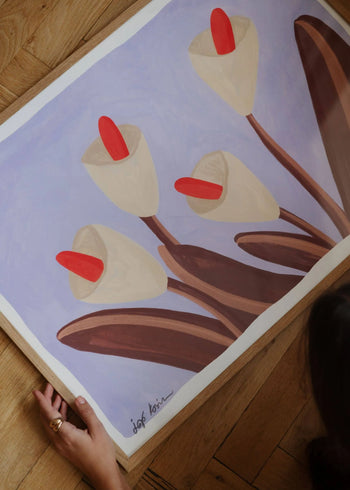 A person holds The Poster Clubs Iga Kosicka - Flowers 03 (30x40) art print, showing abstract cream-petaled flowers with red centers on a soft lavender background, featuring the artists signature in the bottom left.