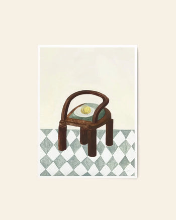 The Poster Club’s Isabelle Vandeplassche - Chair With Fruit (50x70) art print depicts a wooden chair with curved arms, a lemon on the seat, and a checkered tile floor against an off-white background in signature The Poster Club style.