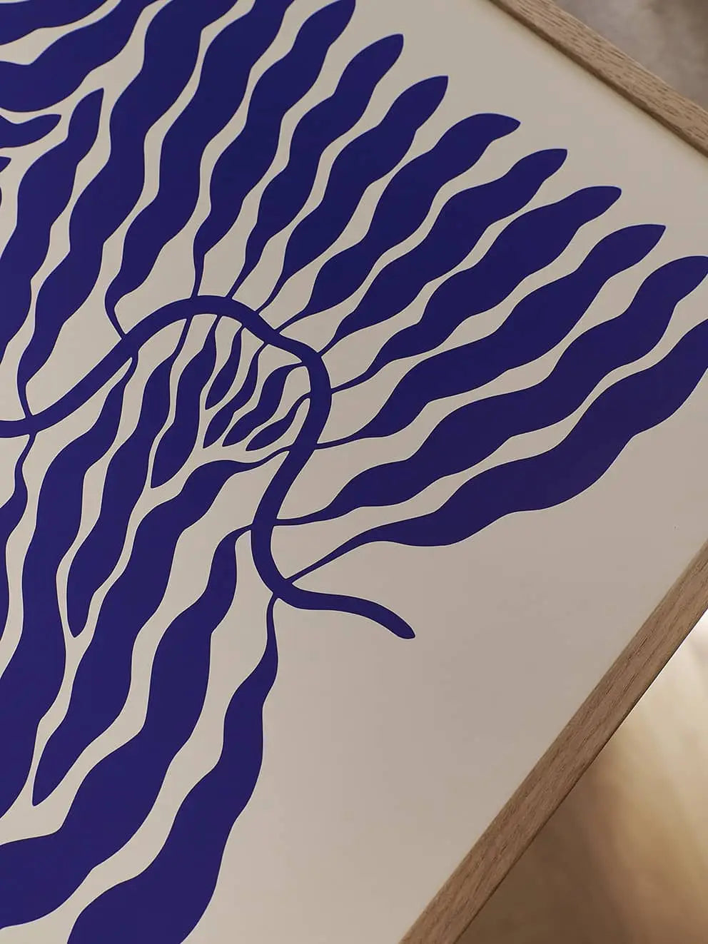 Flowers in Blue Vase (50x70) by Madelen Möllard for The Poster Club is an abstract art print with wavy blue lines on white, framed in light wood, evoking stylized plant leaves or seaweed.