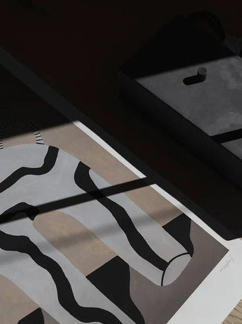 The Poster Club Studio Paradissi - Veins 01 (50x70) by The Poster Club features bold black and white wavy lines on a tan and gray background, partly in shadow. A shaded rectangular black object with a small knob sits nearby.