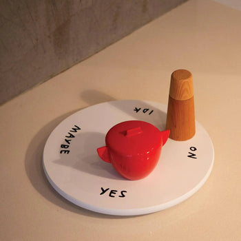 The Third Drawer Down Adam JK - Indecisive Lazy Susan is a playful round white board with YES, NO, MAYBE, and IDK at the edges, plus a red container and wooden spinner—perfect for making decisions fun.