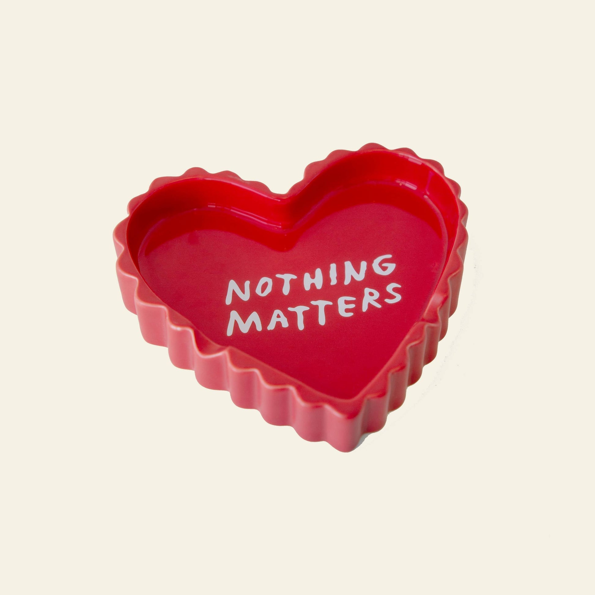 The Third Drawer Down Adam JK - Nothing Matters Ceramic Tray features a playful red heart shape with wavy edges and bold white “NOTHING MATTERS” text, offering a whimsical message from the Third Drawer Down brand.