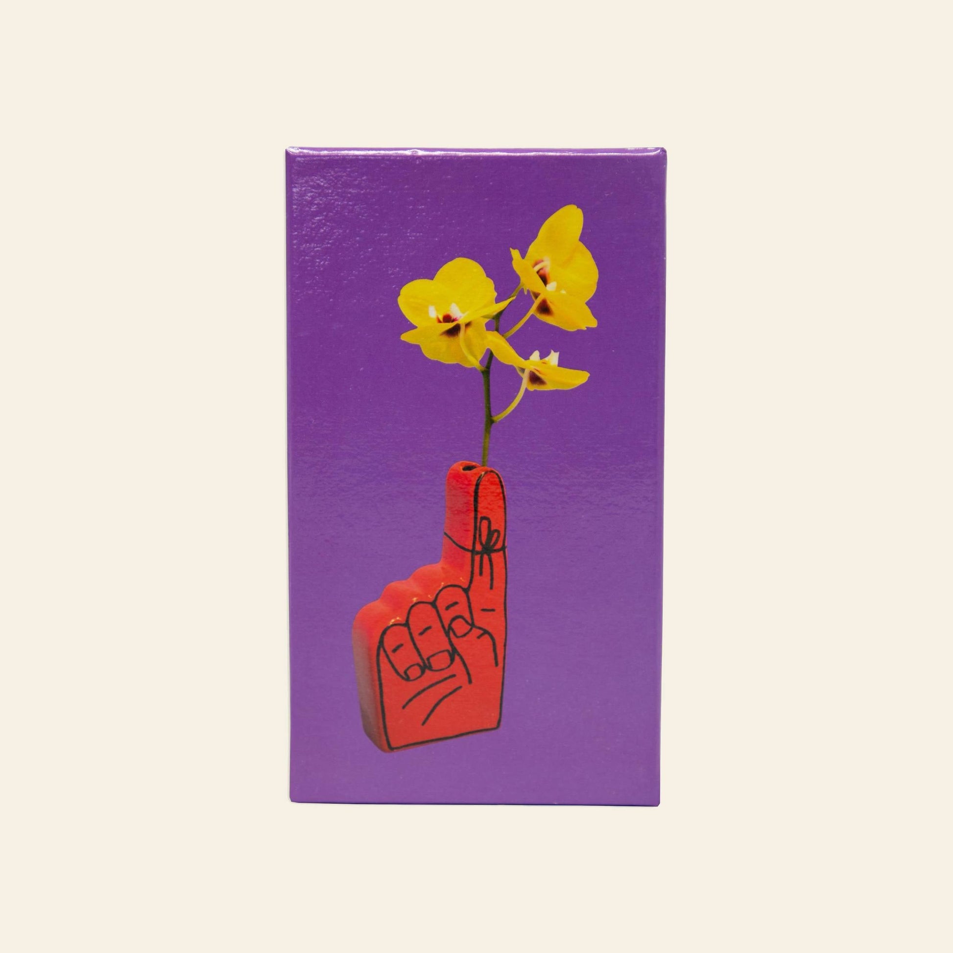 The Third Drawer Down Adam JK - Remember Bud Ceramic Vase features a red foam finger tied with a string to its raised finger, holding two yellow flowers. This vase sits in a purple box against a light beige background.
