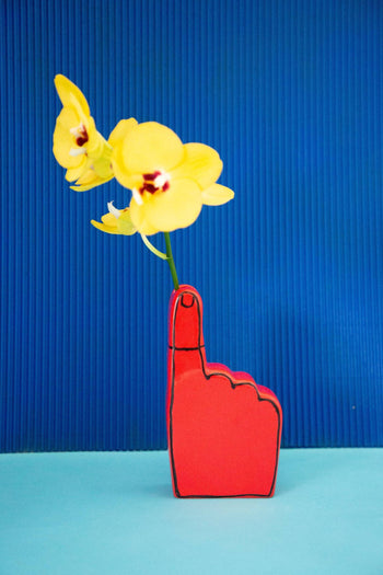 The Third Drawer Down Adam JK - Remember Bud Ceramic Vase by Third Drawer Down sits against a blue ridged background and light blue surface, creating a playful setting that celebrates memories in vibrant color.