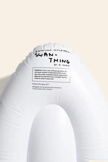 The Third Drawer Down David Shrigley - Ridiculous Inflatable Swan-Thing is a white inflatable swan float featuring printed text by David Shrigley at the top, plus a warning label and extra info on the float.