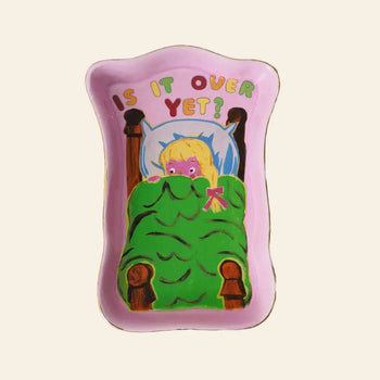 The Third Drawer Down Magda Archer - Is It Over Yet Trinket Tray is a pink ceramic rectangle showing a cartoon figure with blonde hair under a green blanket and colorful Is it over yet? text—ideal for storing jewelry or trinkets.