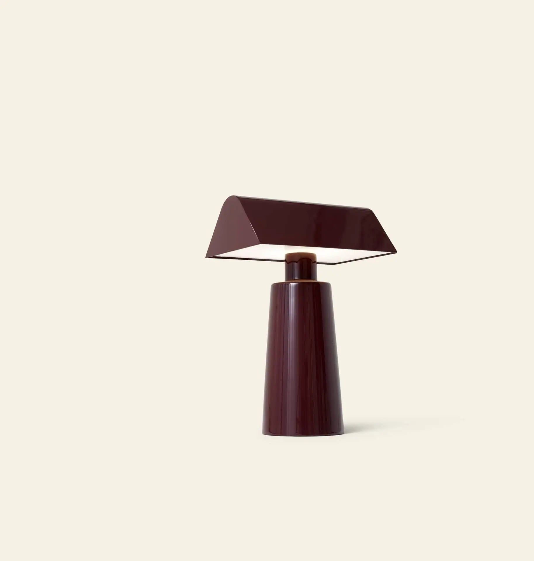 The &Tradition Caret MF1 Portable Table Lamp by &Tradition features a modern, minimalist design with a glossy dark burgundy finish and an angled rectangular shade, shown against a plain light beige background.