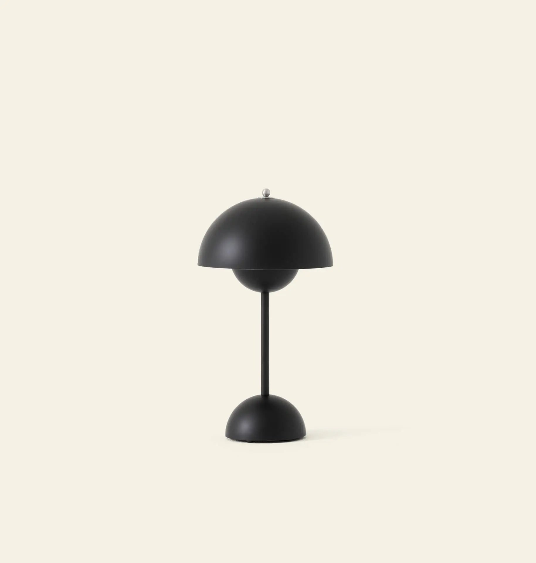 The &Tradition Flowerpot VP9 Portable Table Lamp by &Tradition is a modern black lamp with a dome-shaped shade and base, shown against a light beige background. This minimalist, symmetrical design includes a USB charging cable for convenience.