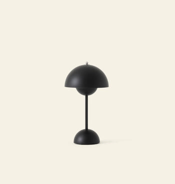 The &Tradition Flowerpot VP9 Portable Table Lamp by &Tradition is a modern black lamp with a dome-shaped shade and base, shown against a light beige background. This minimalist, symmetrical design includes a USB charging cable for convenience.