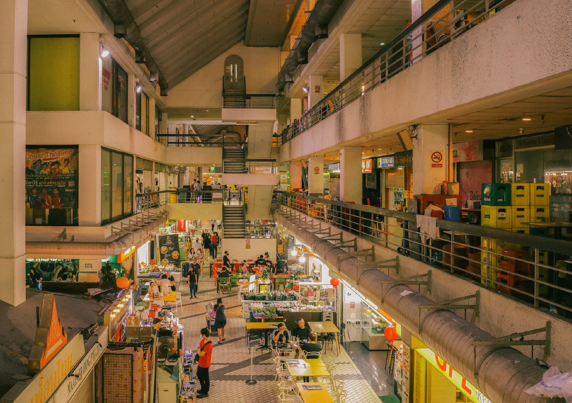 UNIT. Volume 2: Golden Mile Complex by UNIT. captures the vibrant indoor market with multiple levels, food stalls, vendors, and diners beneath warm yellow lights; stairs and colorful signs inspire lively architectural conversations.