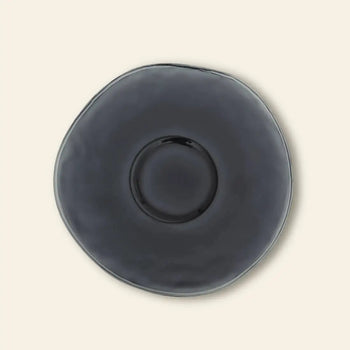 The Urban Nature Culture Dinner Plate Recycled Glass features an irregular shape and glossy dark gray finish, giving it a rustic feel against a plain light beige background.