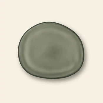 The Urban Nature Culture Plate Recycled Glass Frost by Urban Nature Culture is centered on a plain beige background, its irregular shape and frosted finish highlighting earthy tones that accentuate its natural beauty.