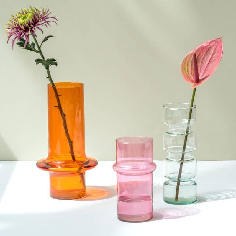 Three colorful glass vases, including the Urban Nature Culture Vase Recycled Glass in pink, stand on a white surface casting soft shadows. This Urban Nature Culture piece adds fresh elegance and style to any room decor.