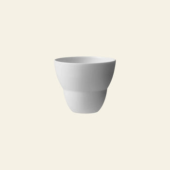 A set of two Vipp Vipp202 coffee cups by Vipp, crafted from high-quality porcelain with a smooth, minimalist design, is centered on a light beige background.