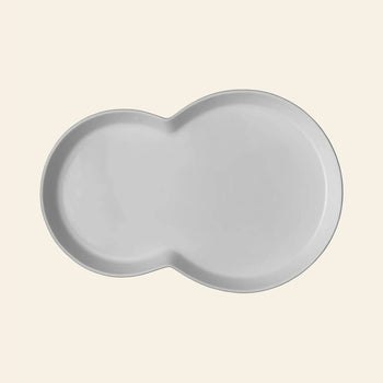The Vipp Vipp214 Brunch Plates, Set of 2 by Vipp feature a white, kidney-shaped ceramic design with smooth edges—ideal as a modern centerpiece for stylish gatherings. Shown here against a plain light beige background.