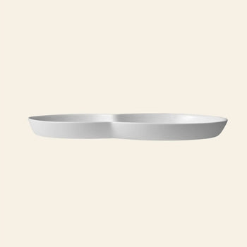 The Vipp Vipp214 Brunch Plates, Set of 2 by Vipp features white, oval-shaped ceramic plates with a gentle central dip—perfect as modern centerpieces for stylish gatherings, shown against a plain beige background.